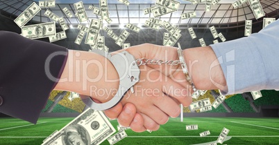 Business people with handcuffs shaking hands at football stadium representing corruption