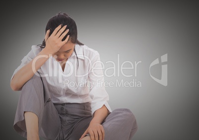 Stressed business woman sitting down against grey background