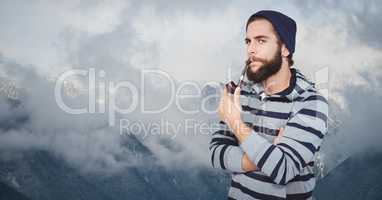 Hipster smoking pipe against mountains
