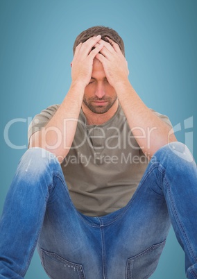 Man sitting with hands on head against blue background