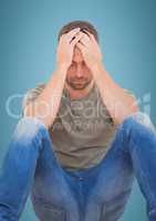 Man sitting with hands on head against blue background