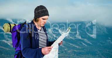 Traveler reading map while carrying backpack on mountain
