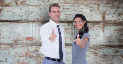 Portrait of confident business people showing thumbs up against wooden wall