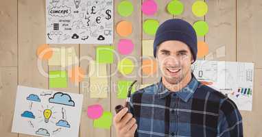 Portrait of young man holding tobacco pipe against sticky notes and drawings on wall