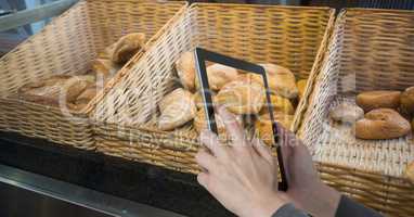 Hands photographing breads on tablet PC at coffee shop