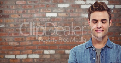 Handsome man with eyes closed against brick wall