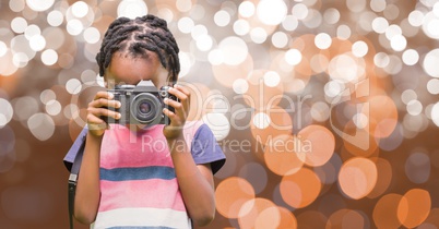 Little girl using digital camera over bokeh