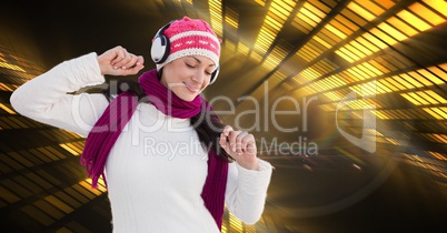 Woman in warm clothing listening to music through headphones