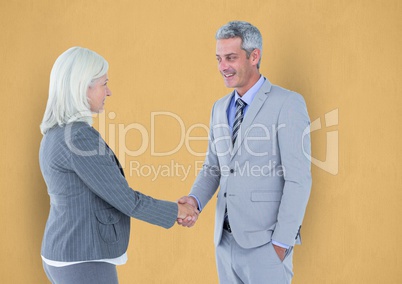 Business people shaking hands against yellow background