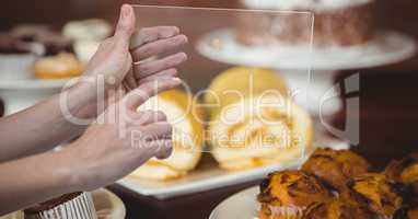 Hands taking picture of dessert with transparent device in coffee shop