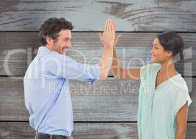 Happy business people giving high-five against wooden wall