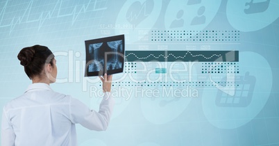Digitally generated image of female doctor holding x-ray against futuristic screen