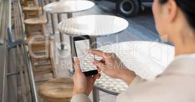 Businesswoman taking picture with mobile phone in coffee shop