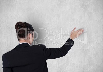 Rear view of businesswoman with arm raised against wall