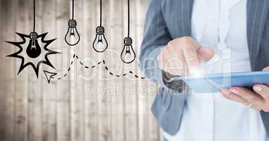 Business woman mid section touching tablet with flare against lightbulb graphics and blurry wood pan