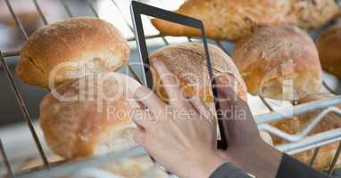 Hands photographing breads through tablet computer in grocery store