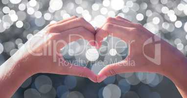 Cropped image of couple making heart shape with hands over bokeh