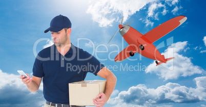 Delivery man using mobile phone while holding parcel against airplane flying in sky