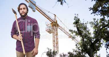 Hipster holding ax against crane