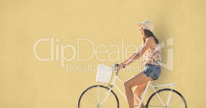 Side view of woman riding cycle over beige background