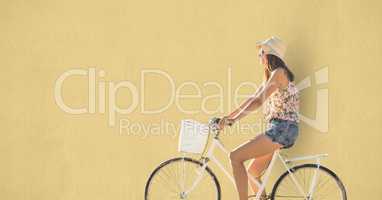 Side view of woman riding cycle over beige background