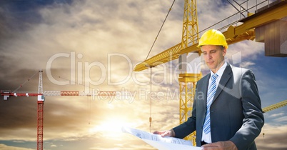 Architect looking at blueprint against crane
