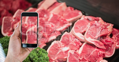 Hand photographing meat through smart phone in grocery store