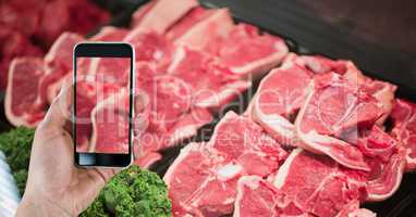 Hand photographing meat through smart phone in grocery store