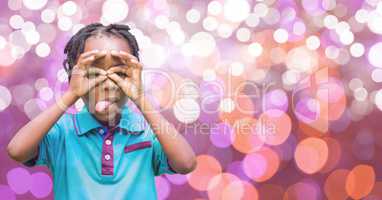 Playful boy sticking out tongue over bokeh