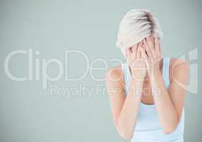 Woman crying into hands against light blue background