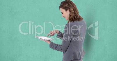 Smiling businesswoman touching screen of tablet PC over turquoise background