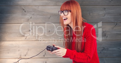 Redhead woman playing video game against wooden wall