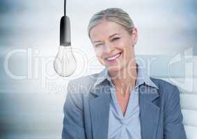 Business woman in chair with glowing lightbulb against blurry blue wood panel