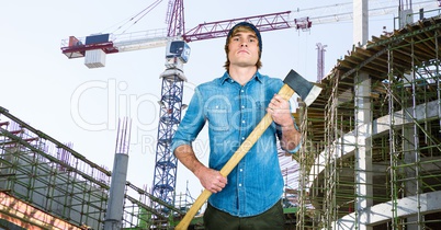 Confident hipster holding ax against incomplete buildings