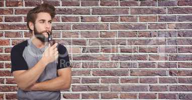 Hipster smoking pipe against brick wall