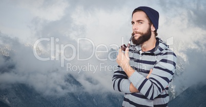 Confident hipster smoking pipe against mountains
