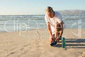Senior man tying shoelace at beach