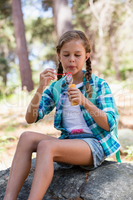 Girl sitting on the rock and blowing bubbles