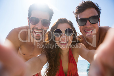 Low angle portrait of smiling young friends against clear sky