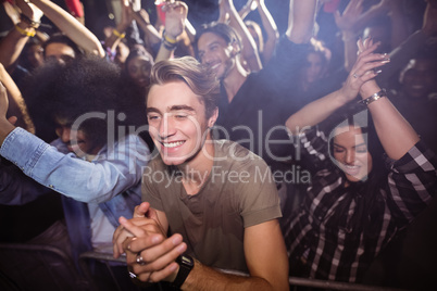 Young man amidst crowd enjoying at nightclub