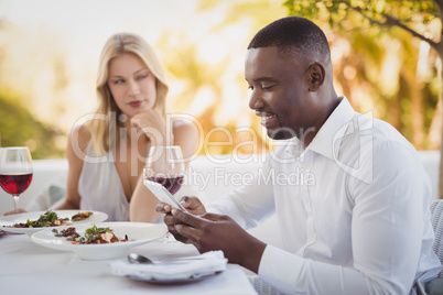 Man ignoring bored woman while using mobile phone