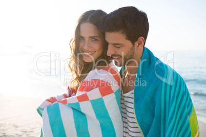 Happy young couple wrapped in blanket at beach