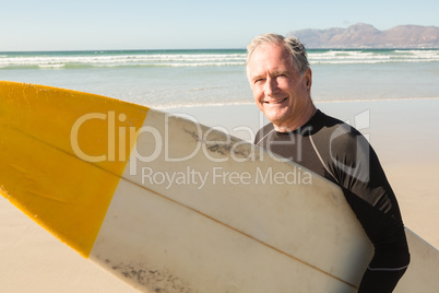 Portrait of smiling senior man with surfboard