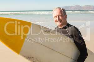 Portrait of smiling senior man with surfboard