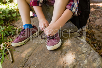 Boy tying shoelace in the forest