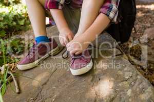 Boy tying shoelace in the forest
