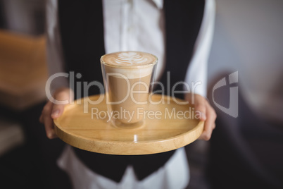 Mid-section of waitress holding tray with glass of coffee
