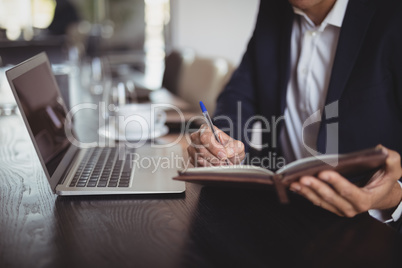 Businessman writing on diary