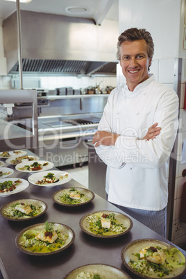 Portrait of happy chef with appetizer plates at order station
