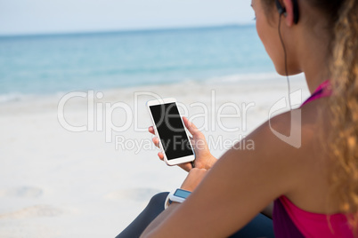 Mid section of woman using mobile phone at beach